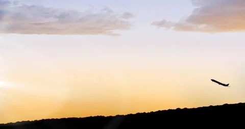 Animation of silhouetted plane taking off over field and orange sky at sunset Stock Footage 151870618