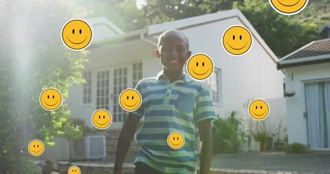 Animation of smiley faces over happy african american boy in garden Stock Footage 328351215
