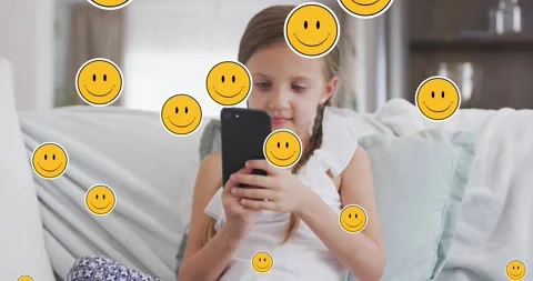 Animation of smiley faces over happy caucasian girl using smartphone at home Stock Footage 329217991