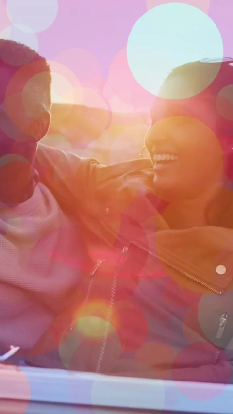 Animation of spots over happy diverse couple embracing in car Vídeo Stock 342315963