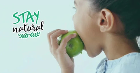 Animation of stay natural text over biracial girl eating green apple Stock Footage