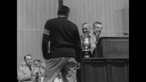 ANNAPOLIS - 1957 - A midshiftman wearing a varsity jacket holds his trophy in Stock Footage 312791175