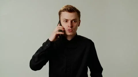 Annoyed angry guy has a phone call. Worried young man in black shirt answer Stock Footage 258620053