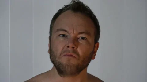 An annoyed bearded man comes into frame. He gives angry looks and shakes Stock Footage 146760397