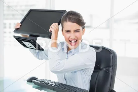 Annoyed classy brown haired businesswoman throwing her computer screen Stock Photos