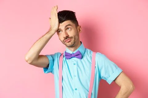 Annoyed guy with suspenders and bow-tie, facepalm with eyes rolled up, standing Stock Photos