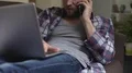 Annoyed man having conversation over mobile phone and using laptop, negative HD Footage
