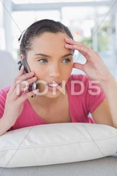 Annoyed woman lying on sofa and calling on phone Stock Photos