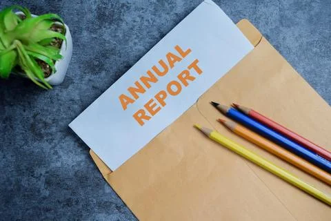 Annual report text on document above brown envelope. Stock Photos