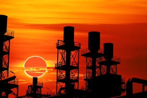 Annular eclipse back over silhouette refinery industry sunset sky Stock Photos