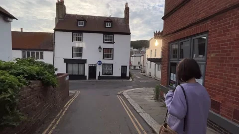 Anonymous brunette walking through the medieval town in England - gimbal shot Stock Footage 222219199