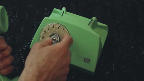 Anonymous caller dialing vintage green rotary phone on black surface Stock Footage 337802116