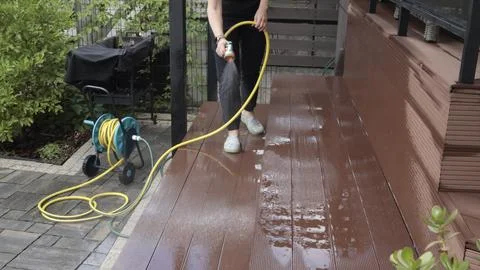 Anonymous cleaning, hose washing deck in summer. Structures in backyard. Clean Stock Photos