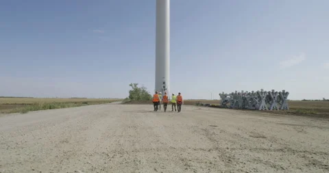 Anonymous colleagues walking towards windmill in countryside Stock Footage 140291434