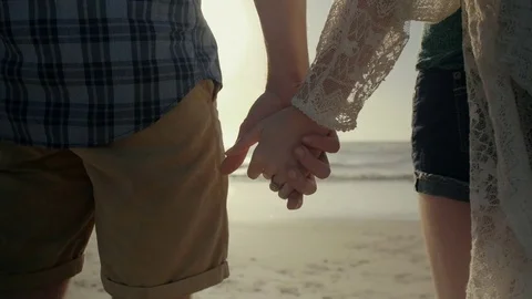 Anonymous couple holding hands on the beach Stock Footage 83359965