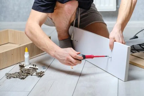 Anonymous craftsman using screwdriver for work with wooden furniture Stock Photos