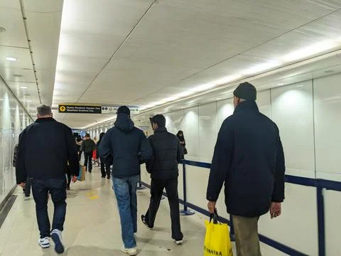 Anonymous crowd of commuters walking through the modern underground passageway Stock Photos