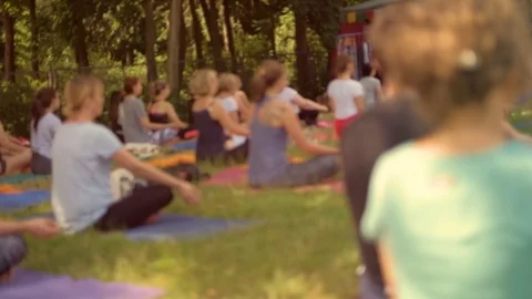 An anonymous crowd practices yoga in the park during a beautiful day Stock Footage 91095174