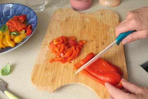 Anonymous cut roasted red pepper on wooden board. Food and healthy eating Stock Photos