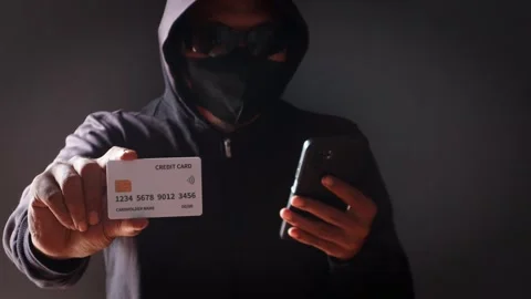 Anonymous cybercriminal using a smartphone and credit Stock Footage 337392748