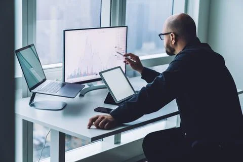 Anonymous dealer watching graph on computer monitor in office Stock Photos