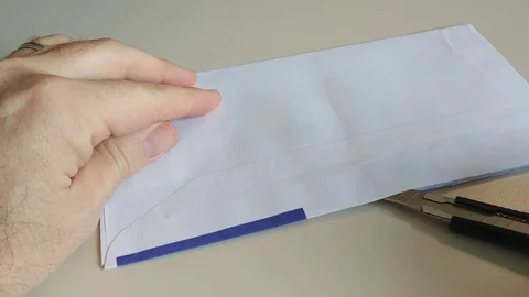 An anonymous envelope is opened with a cutter from the hands of a Caucasian man Stock Footage 121064382