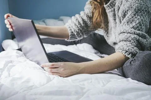 Anonymous female freelancer using computer on bed Stock Photos
