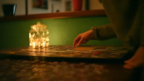 Anonymous female making puzzle at night 動画素材 144698352