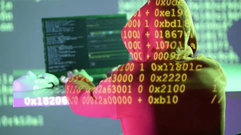 Anonymous figure in hoodie coding intensely with projected hexadecimal data on Stock Footage 307010983