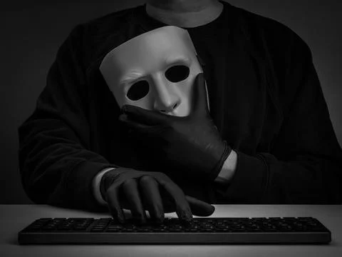 Anonymous figure, scammer or hacker in black gloves holds white mask while .. Stock Photos