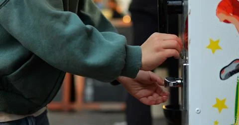 Anonymous five year old child insert coin into gashapon or gumball machine Stock Photos