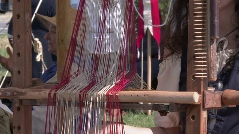 Anonymous girl performs a weaving demonstration at the loom in a medieval camp. Video stock 76140361