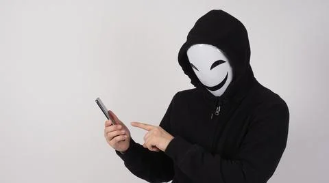Anonymous hacker and face mask with smartphone in hand. Stockfoto's