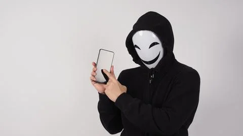 Anonymous hacker and face mask with smartphone in hand. Stockfoto's