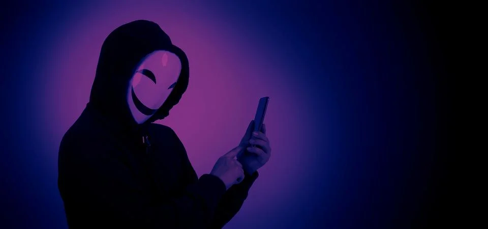 Anonymous hacker and face mask with smartphone in hand. Stock Photos