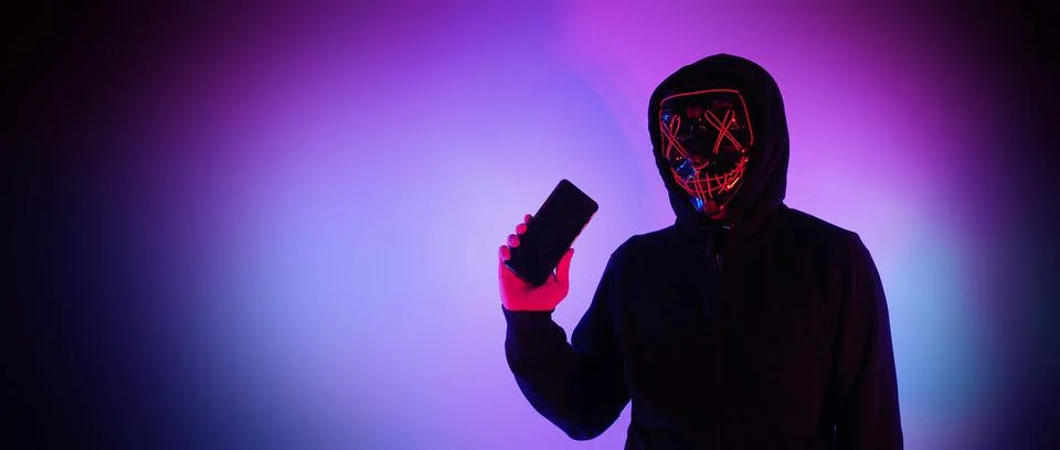 Anonymous hacker and face mask with smartphone in hand. Stockfoto's