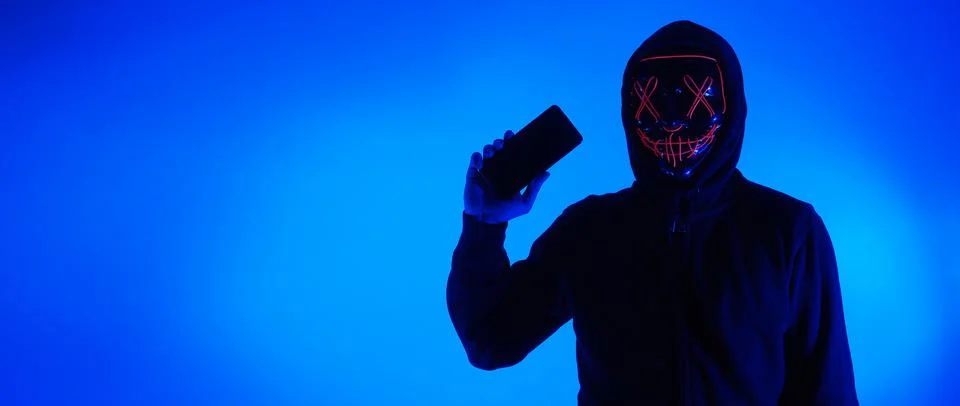 Anonymous hacker and face mask with smartphone in hand. Stockfoto's