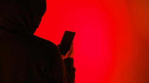 Anonymous hacker and face mask with smartphone in hand. Stockfoto's