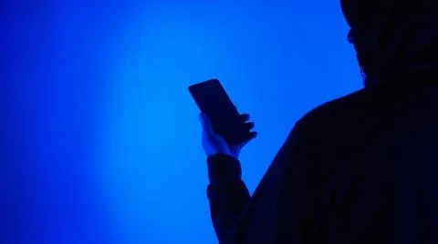 Anonymous hacker and face mask with smartphone in hand. Stockfoto's
