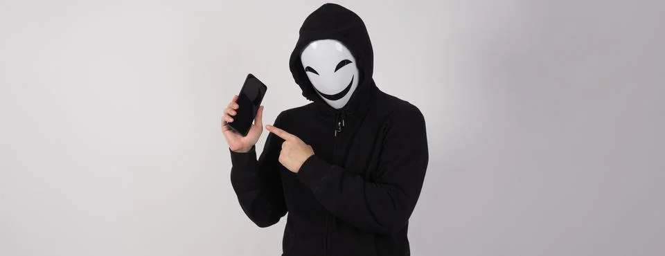 Anonymous hacker and face mask with smartphone in hand. Stock Photos