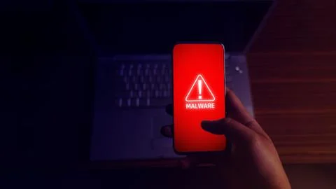 An anonymous hacker and uses a malware with mobile phone to hack password the Stock Photos
