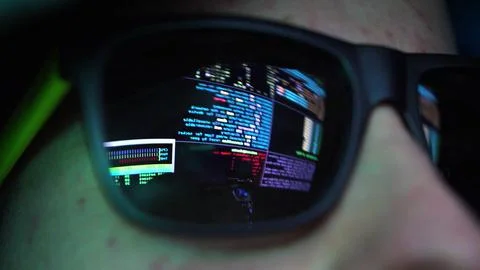Anonymous Hacker in Dark Glasses Looking at Computer Screen Code Reflections Foto stock