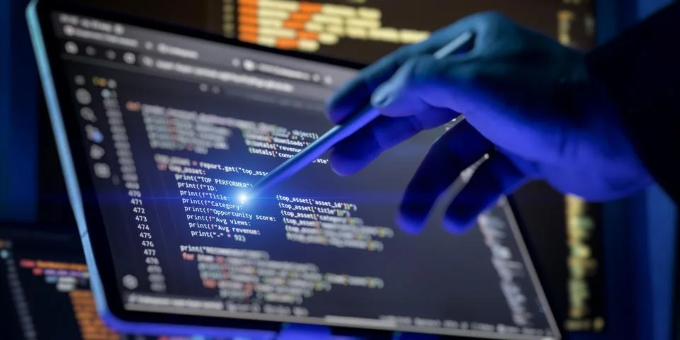 Anonymous hacker in gloves using a digital pen to analyze programming code on Stockfoto's