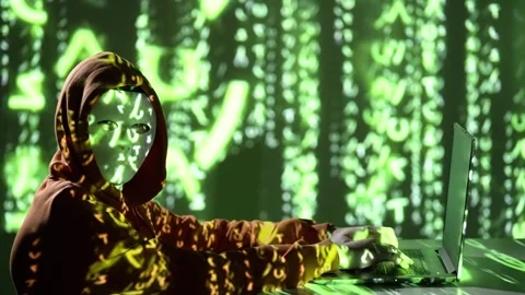 Anonymous Hacker in Hoodie with Mask Using Laptop and Green Code Projection – Stock Footage 307177776