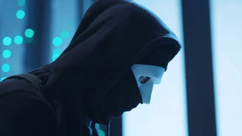 Anonymous hacker in hoodie trying to break a server in data center close-up Stock Footage 120693316