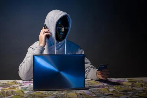 Anonymous hacker in mask programmer uses a laptop to hack the system in the.. Stock Photos