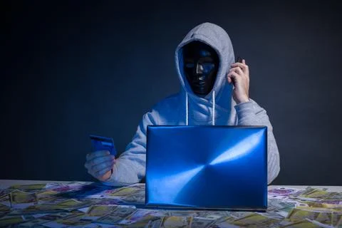 Anonymous hacker in mask programmer uses a laptop to hack the system in the.. Stock Photos