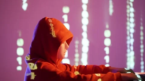 Anonymous hacker in red hoodie with white mask and binary code projection in Stock Footage 307011468