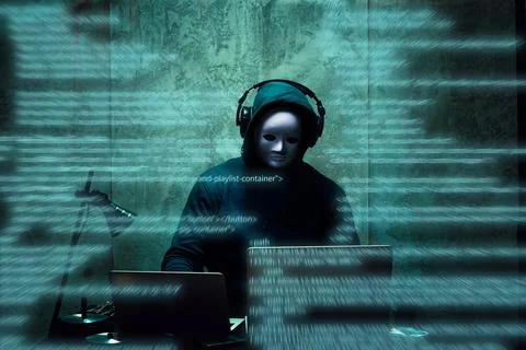 Anonymous hacker wearing face mask working on computer in dark room Stock Photos
