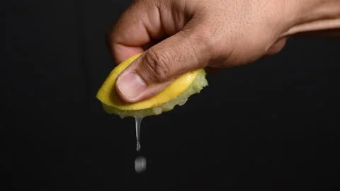 An anonymous hand squeezing a juicy lemon wedge Stock Footage 207466051